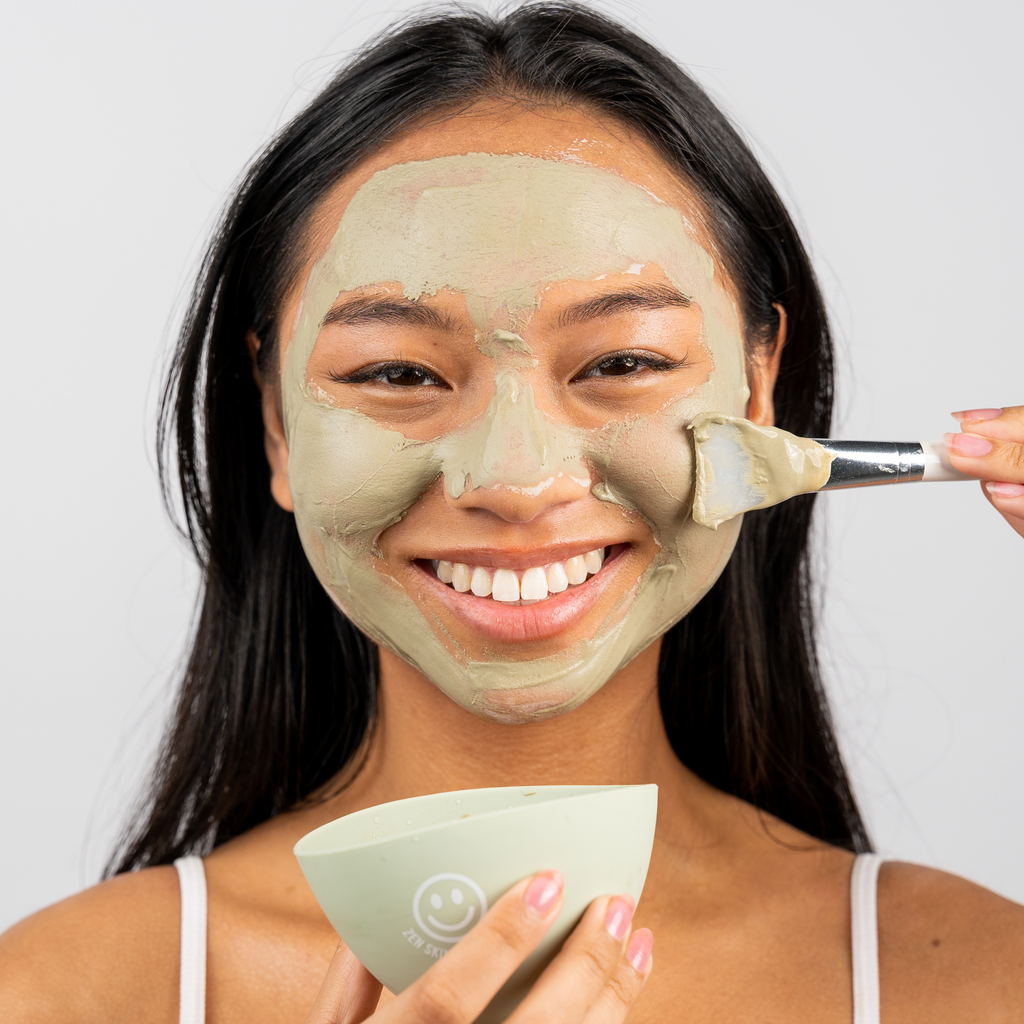 Studio model wearing green clay mask with Zen Botanics silicone clay mask brush and mixing bowl